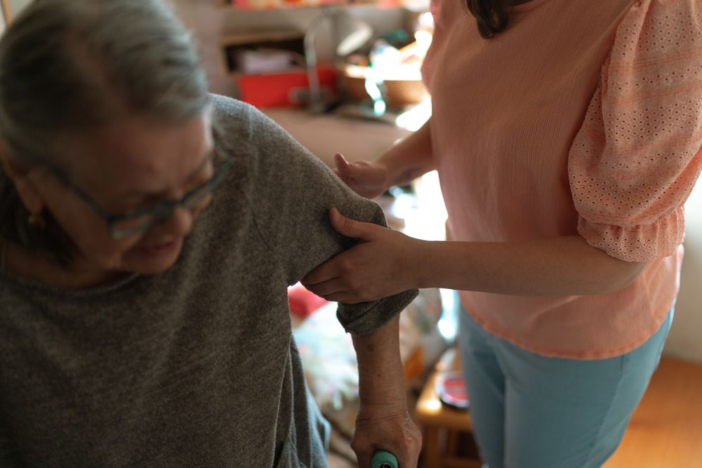 Una cuidadora brinda apoyo a una mujer mayor para desplazarse en casa